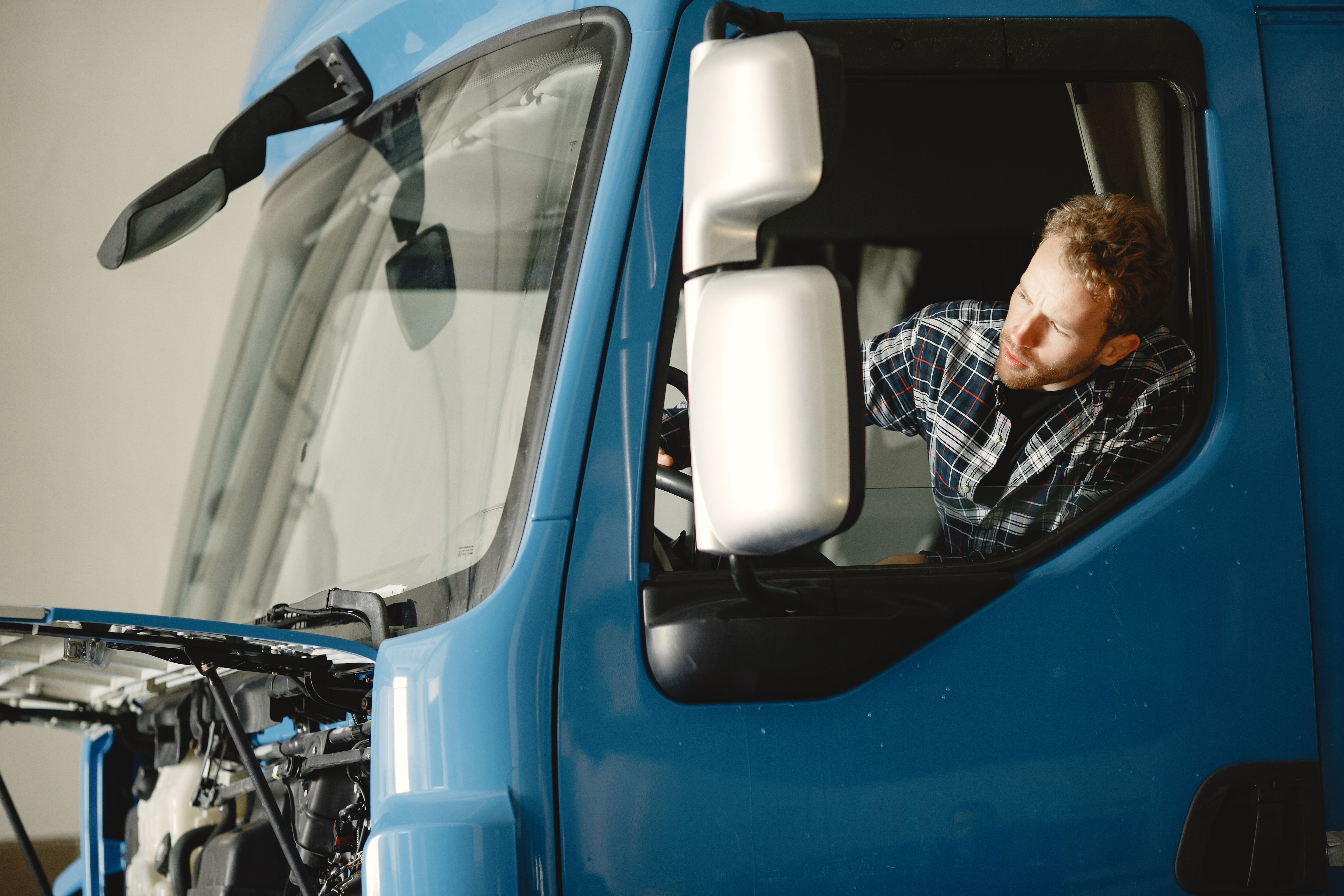 Mechanic inspecting the engine of a truck as part of pre-trip maintenance checks