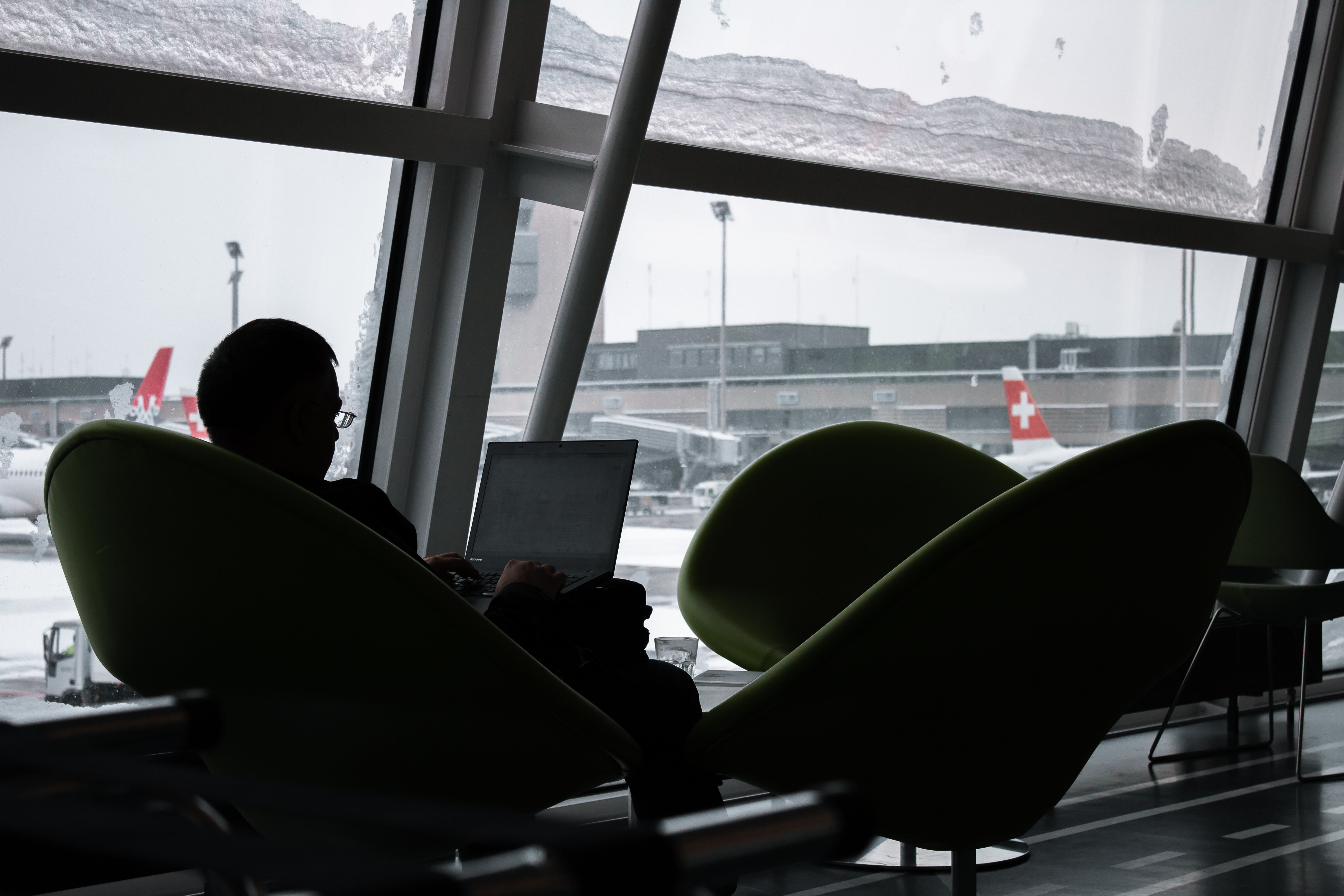 Business traveler working on a laptop at an airport lounge with planes visible outside