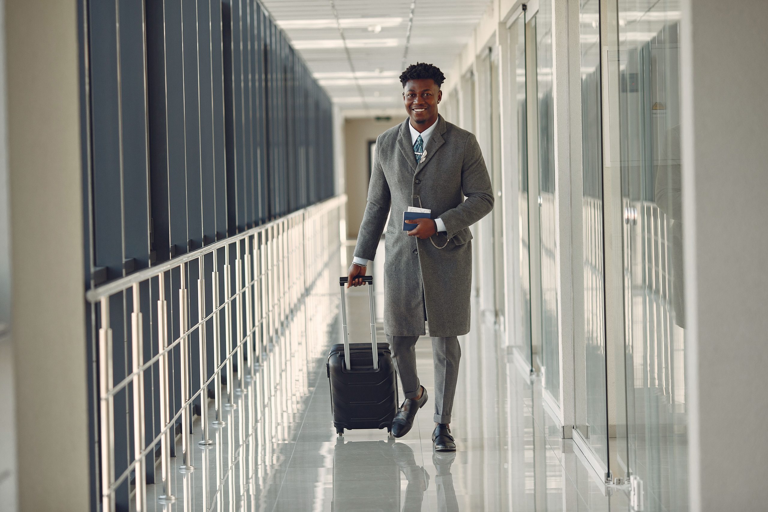 Business traveler walking through a modern airport terminal carrying a suitcase and passport