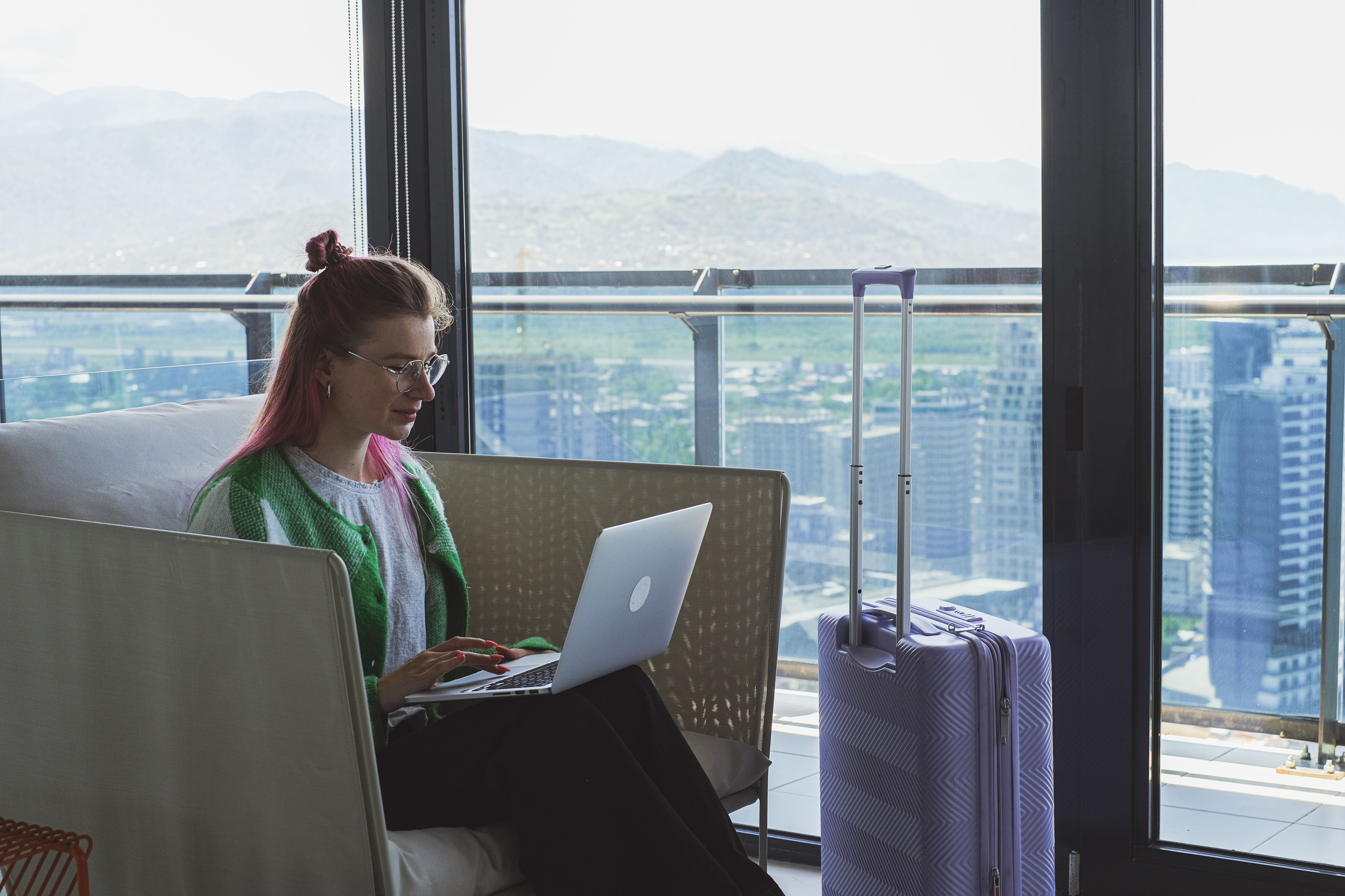 Businesswoman working on a laptop in a hotel lounge overlooking a city skyline