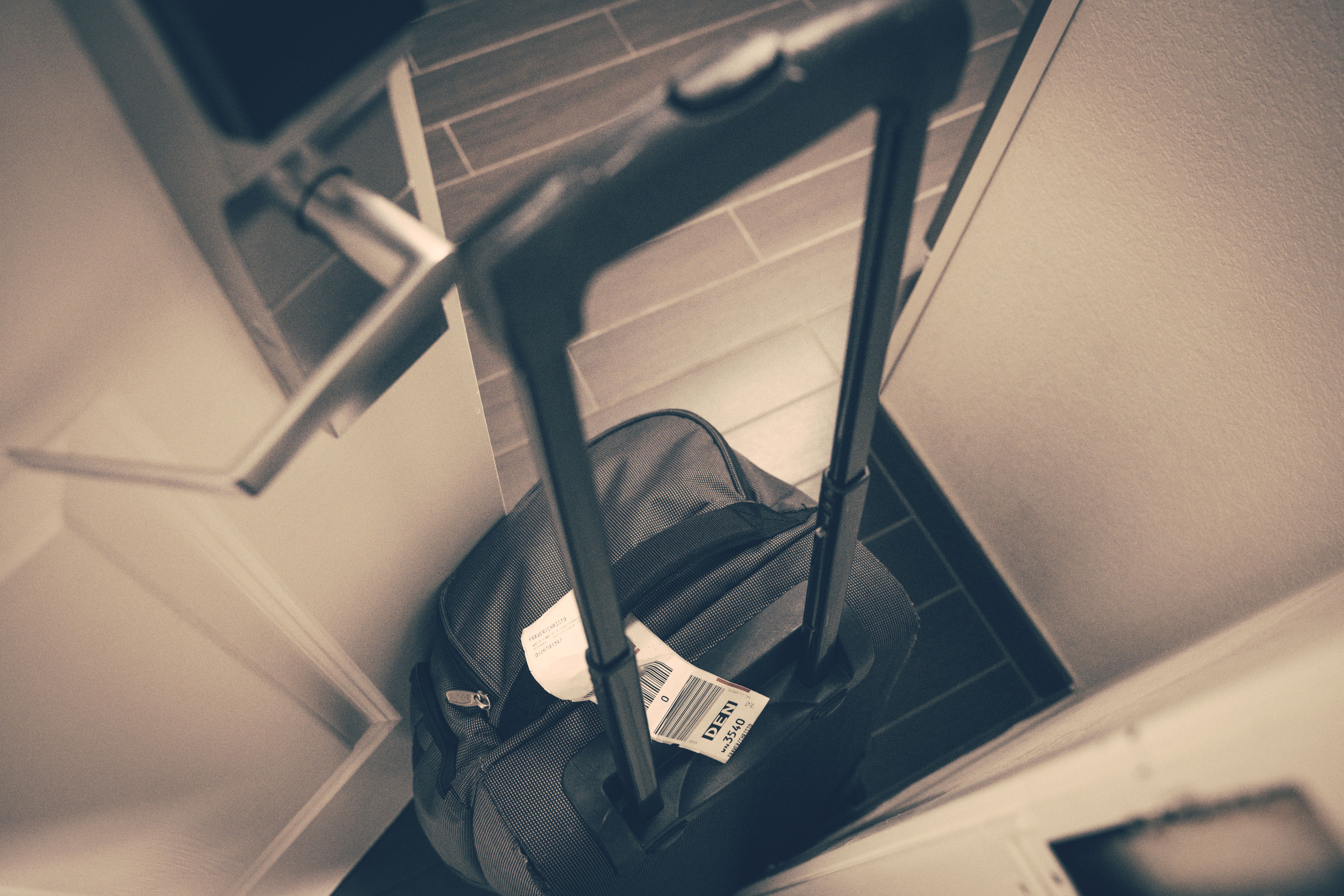 Suitcase with a luggage tag placed by a hotel door ready for travel
